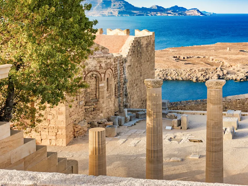 Lindos, Rhodos, Griechenland Antike Säulen und Ruinen mit Blick auf das blaue Meer und felsige Küsten, Lindos, Rhodos, Griechenland.