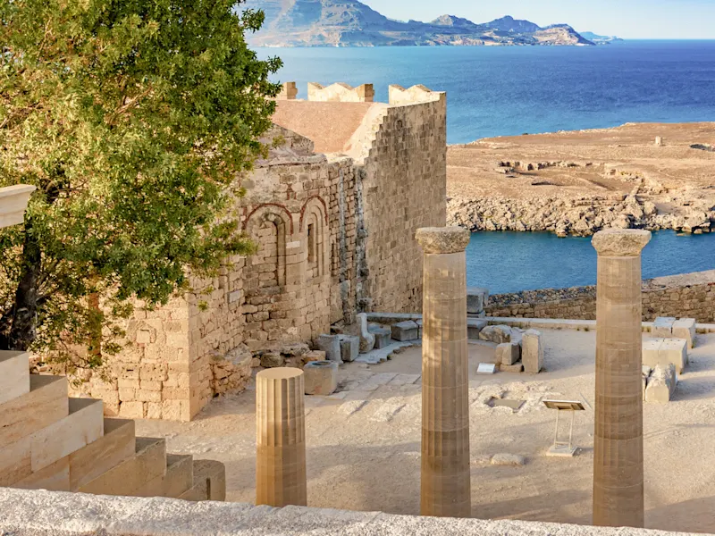 Lindos, Rhodos, Griechenland Antike Säulen und Ruinen mit Blick auf das blaue Meer und felsige Küsten, Lindos, Rhodos, Griechenland.