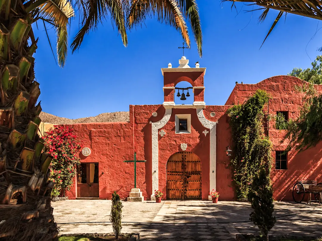 Koloniale Kirche mit roten Mauern, umgeben von Palmen. Nazca, Ica, Peru.