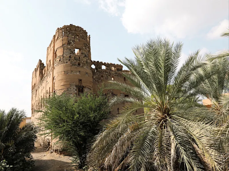 Historisches Gebäude aus Lehmziegeln umgeben von Palmen. Ibra, Ash Sharqiyah, Oman.