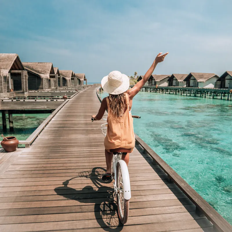 Reiseart, Luxusreisen, Malediven Eine Frau fährt Fahrrad bei einem Resort auf den Malediven.