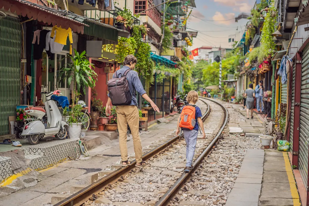 Vater-Sohn-Reisende gehen entlang der Eisenbahnwege, die durch ein Wohngebiet in der Stadt Hanoi führen