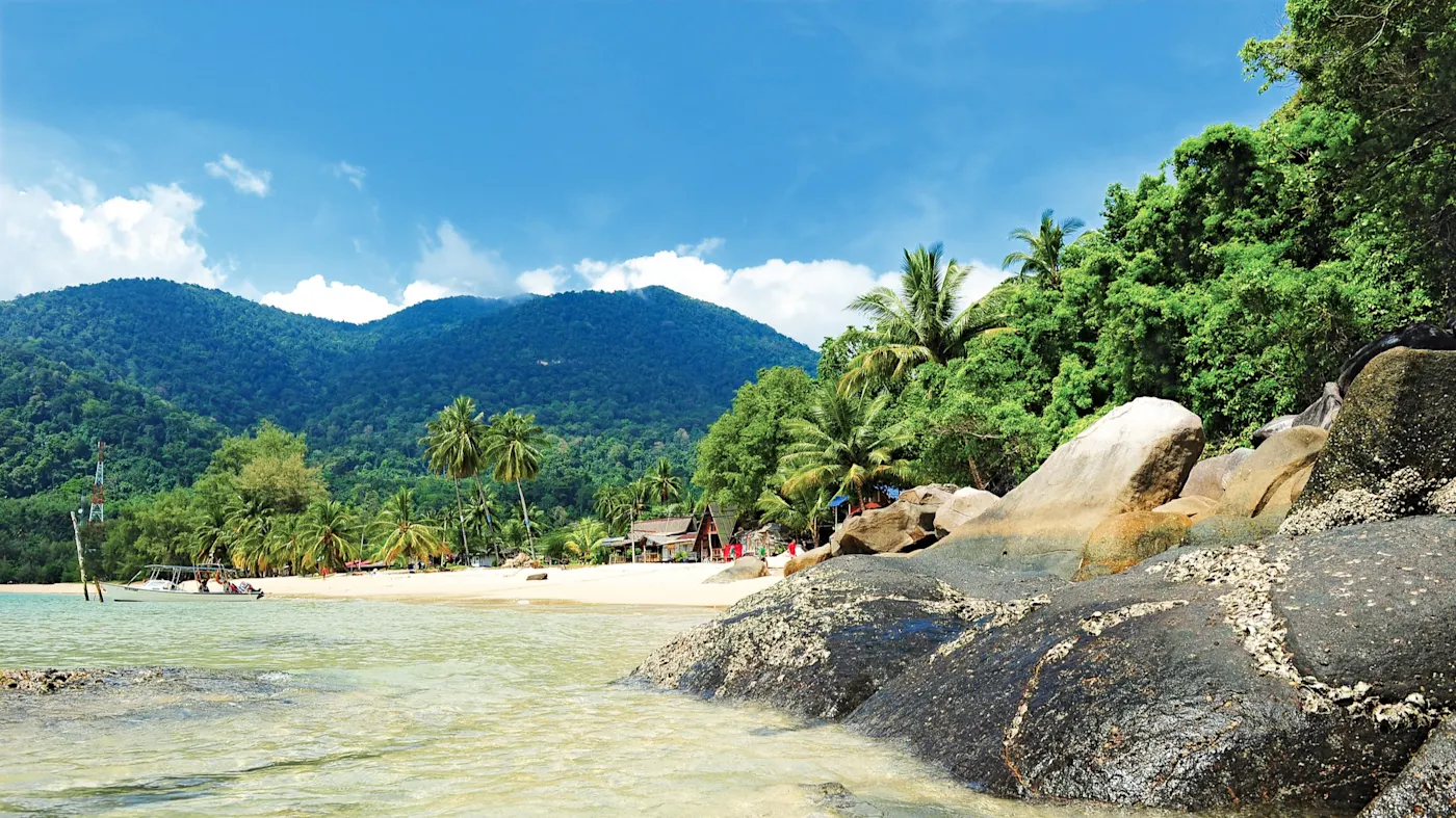 Tioman, Pahang, Malaysia Tropischer Strand mit Palmen, Felsen und klarem Wasser. Tioman, Pahang, Malaysia.