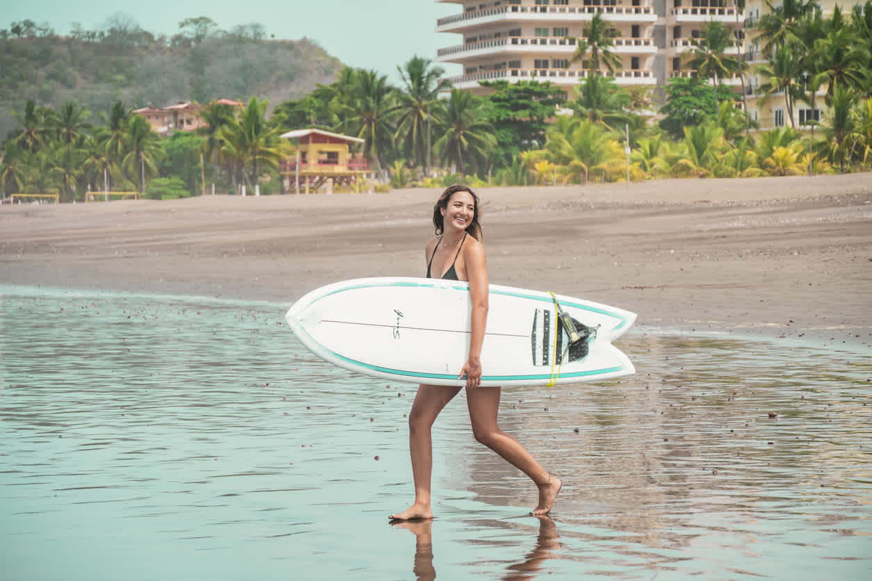 Jeune Femme qui porte sa planche de surf sous le bras