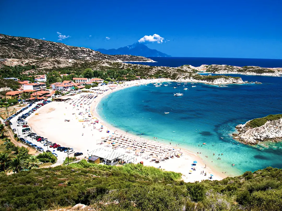 Sandstrand mit klarem Wasser, Sonnenliegen und Blick auf das Meer. Chalkidiki, Griechenland.