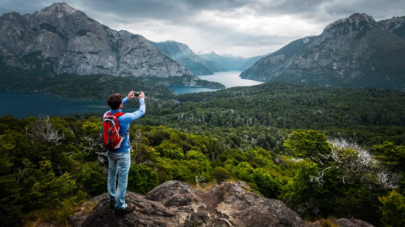 Ein Wanderer, der die Bergkulisse und einen Wald in Patagonien fotografiert