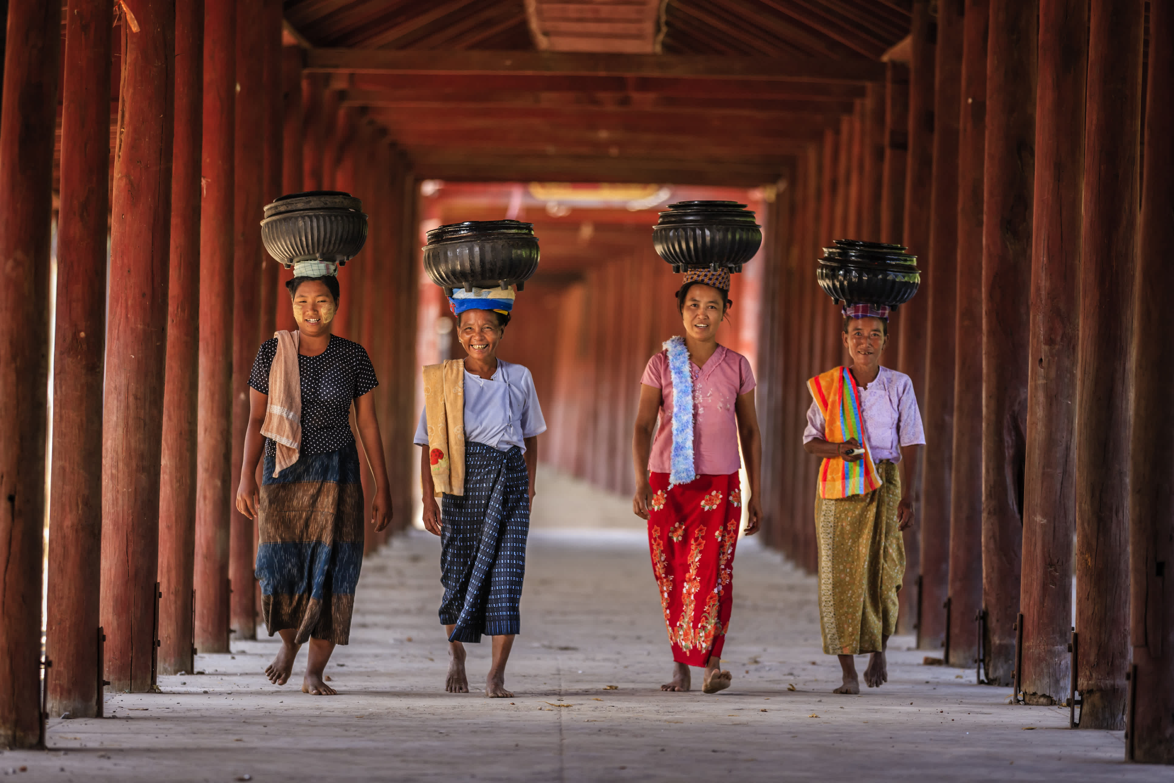 Culture in Myanmar: Burmese women carry rice bowls to the monastery.