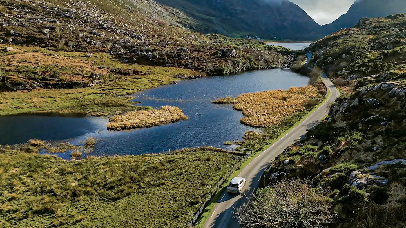Driving on a winding mountain road along the riverbank. Gap of Dunloe, County Kerry, Ireland.