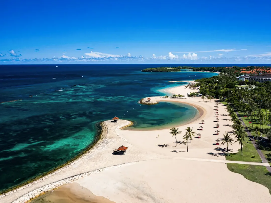  Sandstrand mit ruhigem Wasser und Pavillons. Nusa Dua, Bali, Indonesien.