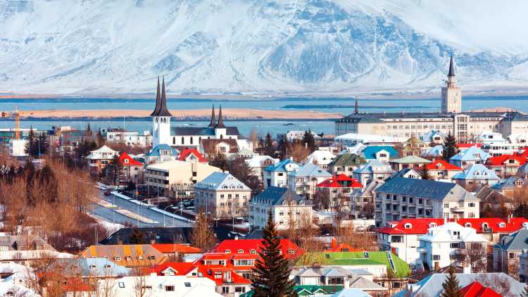 See the Reykjavik skyline, pictured here on a sunny day with mountains in the background, on a Reykjavik vacation.