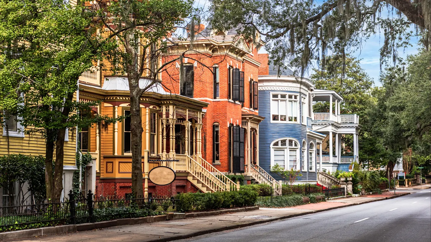 Savannah, Georgia, Vereinigte Staaten Farbenfrohe historische Häuser in einer charmanten Straße mit Bäumen. Savannah, Georgia, Vereinigte Staaten.