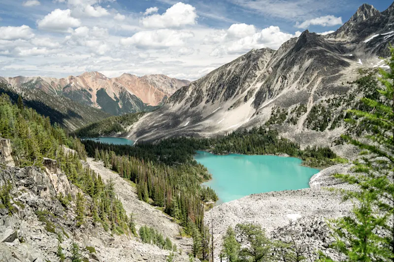 Panoramablick auf einen türkisfarbenen Bergsee umgeben von grünen Wäldern und beeindruckenden Gipfeln. Golden, British Columbia, Kanada.