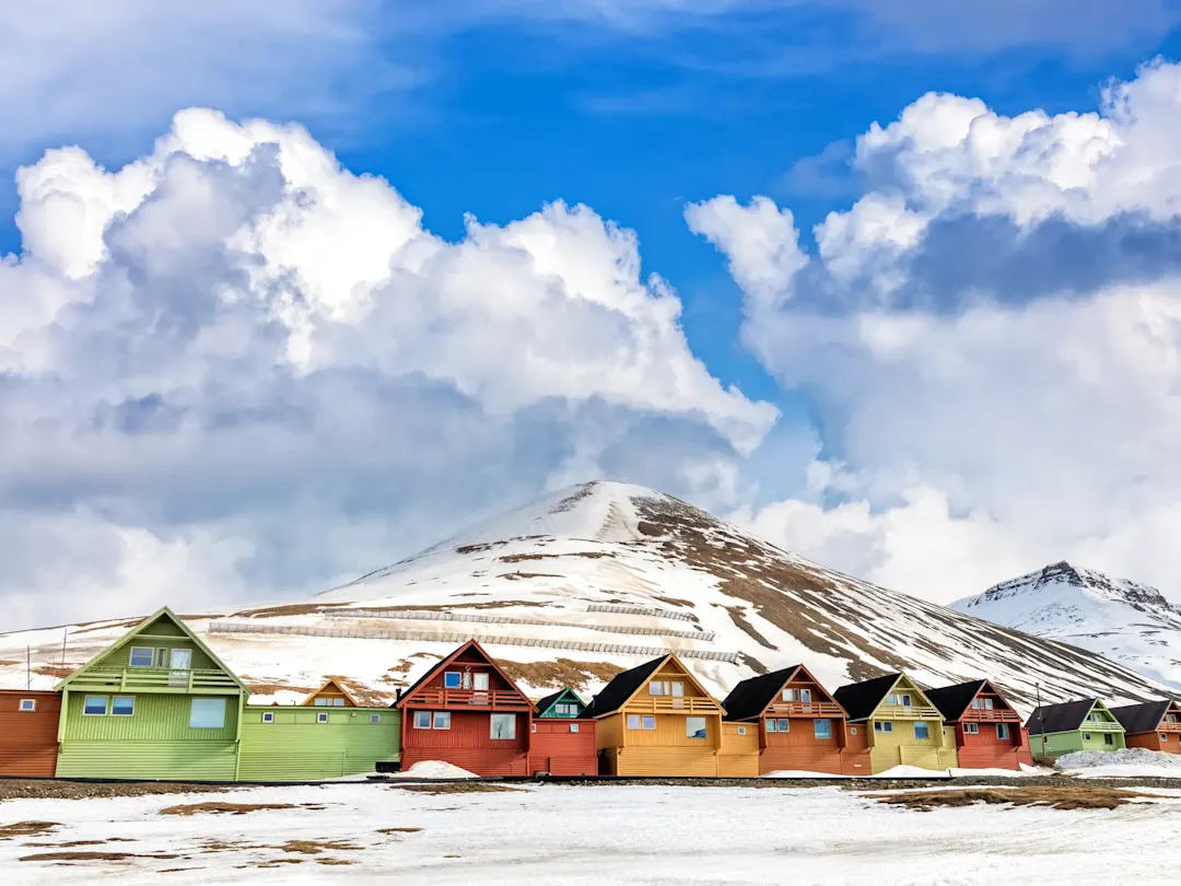 Bunte Holzhäuser vor einer schneebedeckten Berglandschaft. Longyearbyen, Svalbard, Norwegen.