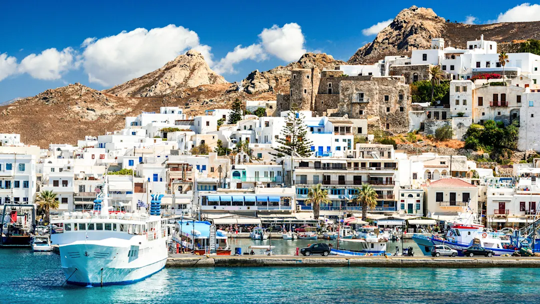 Traditionelle weiße Häuser und eine venezianische Festung am Hafen, umgeben von Booten, Naxos-Stadt, Naxos, Griechenland.