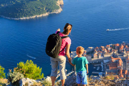 Mutter und Sohn blicken gemeinsam von einem Felsvorscprung auf die Stadt Dubrovnik