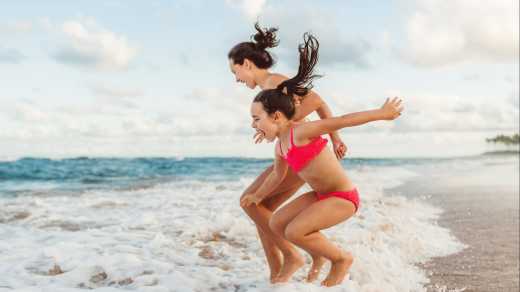 Des sœurs heureuses sautent par-dessus les vagues sur la plage de Bahia, Brésil


