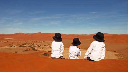 Drei Kinder sitzen auf einer Sanddüne