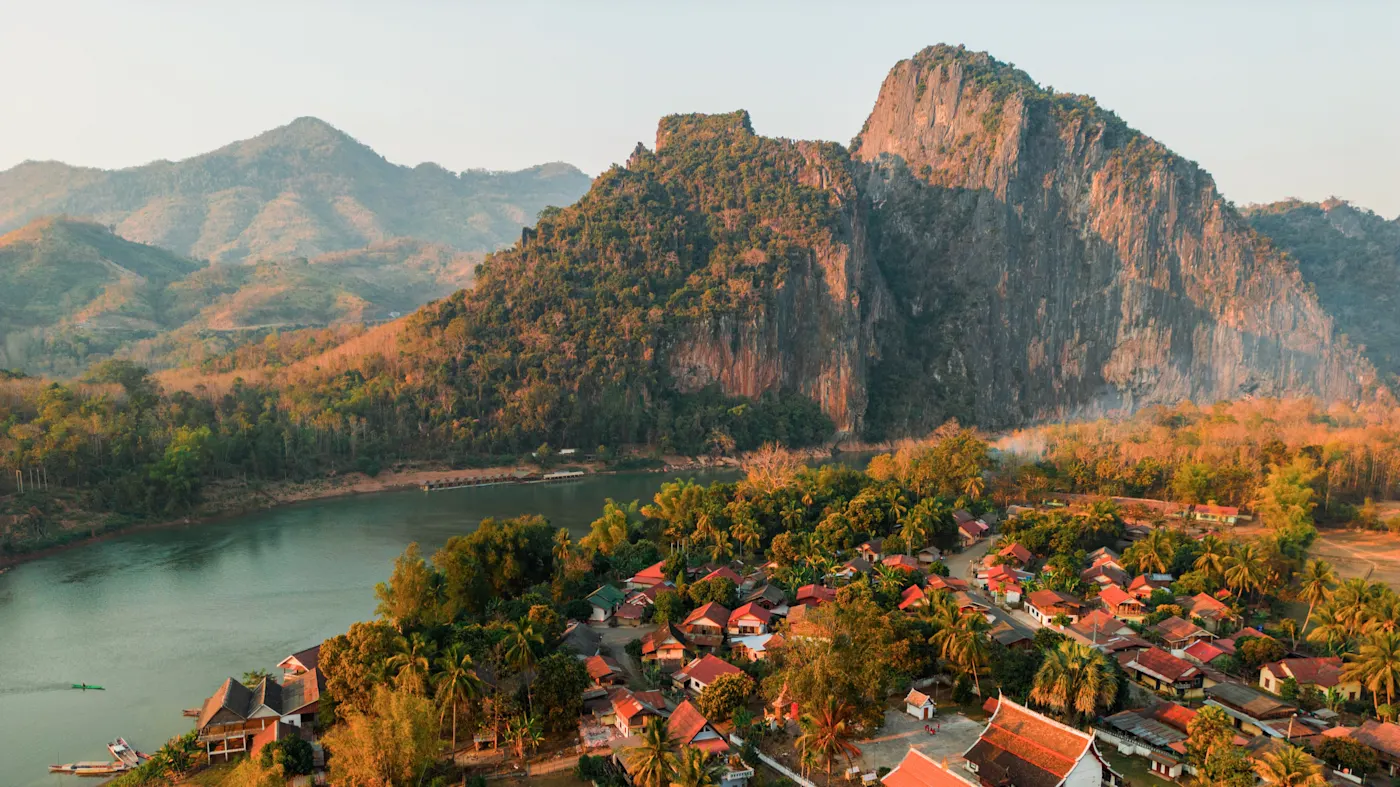 Luang Prabang, Laos Dorf mit roten Dächern am Fluss, umgeben von Bergen im Abendlicht. Luang Prabang, Laos.