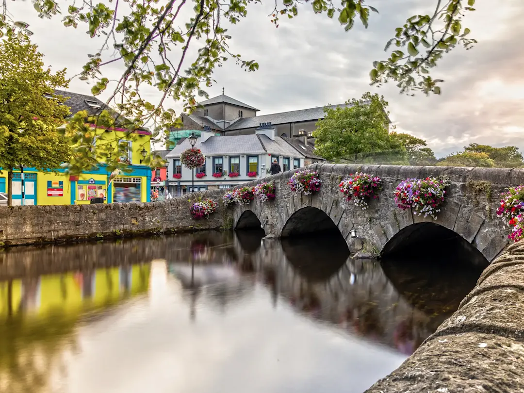 Irland, County Clare, Ennis Malerische Stadtansicht mit blumengeschmückter Steinbrücke. Ennis, County Clare, Irland.