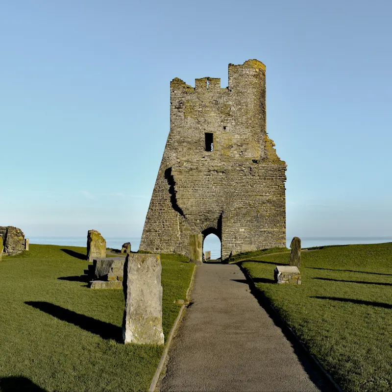 Ruins of a stone tower on a green hill, clear blue sky, historical remains, Aberystwyth Castle, Wales.