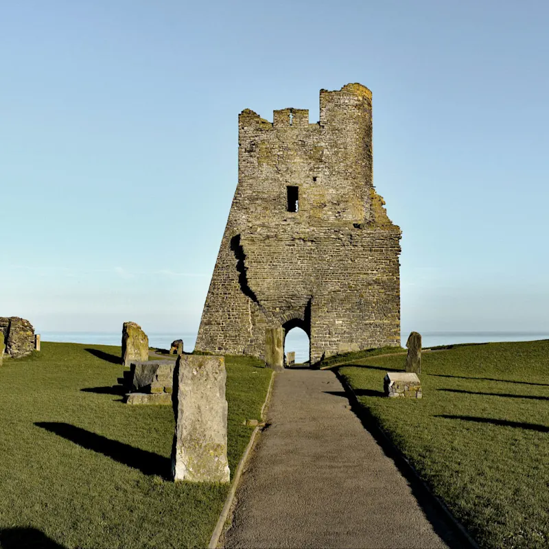 Ruines d'une tour en pierre sur une colline verdoyante, ciel bleu clair, vestiges historiques, château d'Aberystwyth, Pays de Galles.
