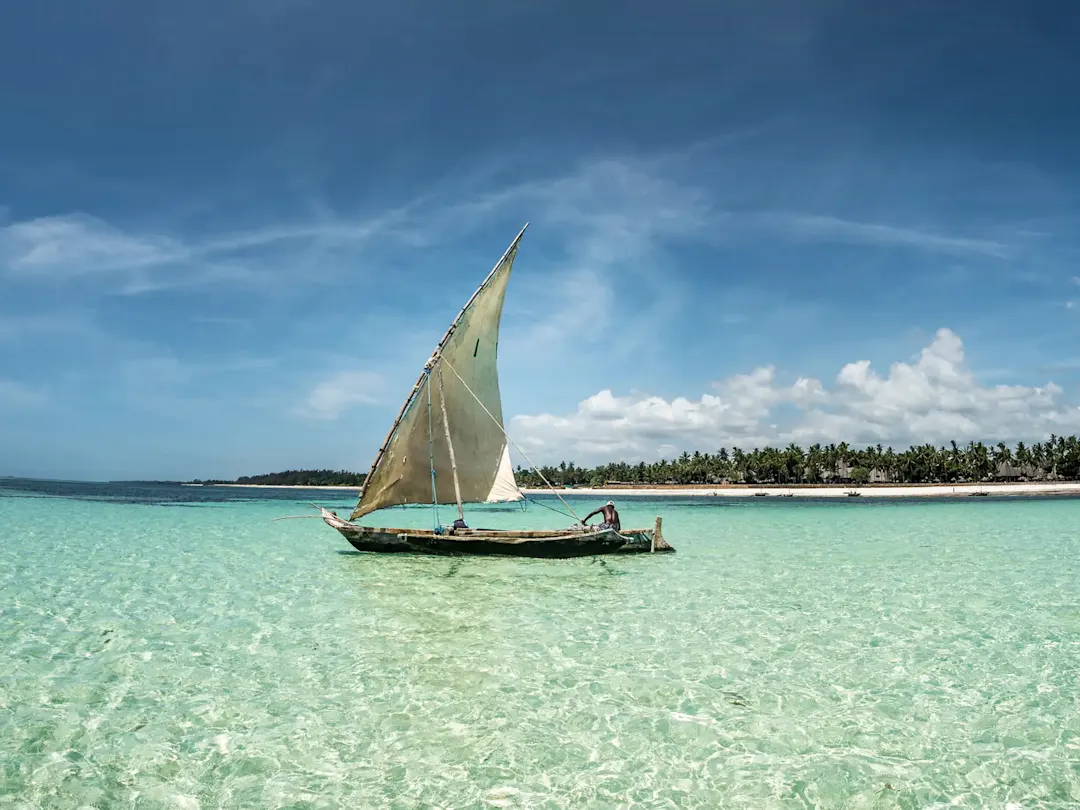 Traditionelles Dhow-Segelboot auf türkisblauem Wasser mit tropischer Insel im Hintergrund. Watamu, Kenia.