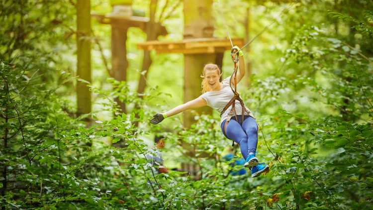 Eine junge Frau bei Ziplining im Wald 