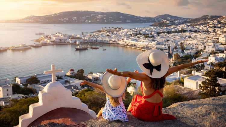 Mutter und Tochter im Familienurlaub mit Blick auf die Stadt Mykonos, Griechenland.