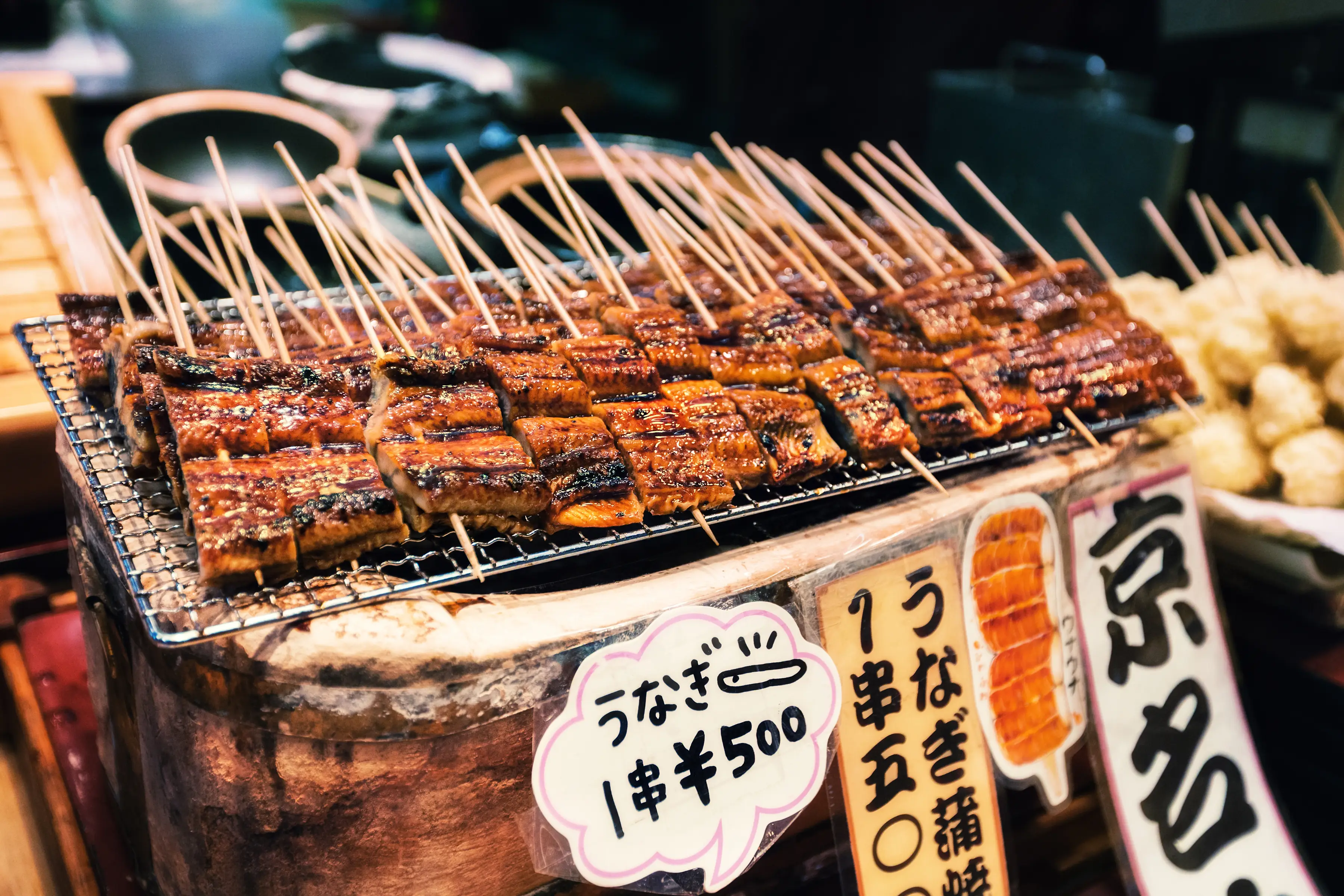 Gegrillte Unagi-Spieße auf Straßenmarkt, mit japanischen Preisschildern, Kyoto, Kansai, Japan