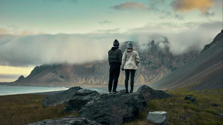Couple se tenant la main devant des montagnes et la mer