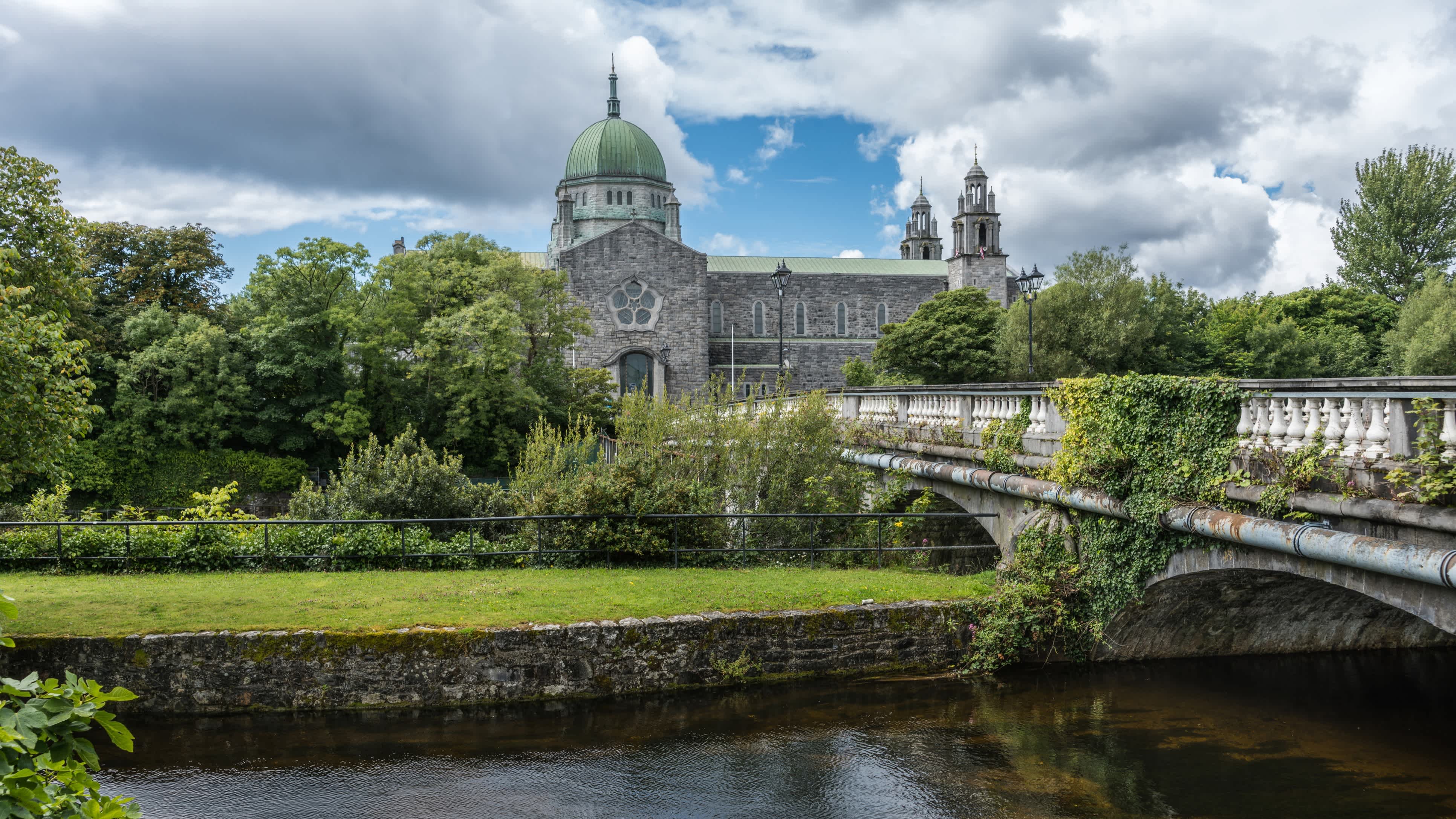 Vue sur un pont entouré de végétation menant à la cathédrale de Galway, en Irlande