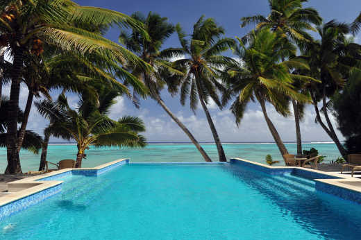Infinity-Pool mit Blick aufs Meer, von Palmen gesäumt - als Sinnbild eines Luxusurlaubs auf den Cookinseln