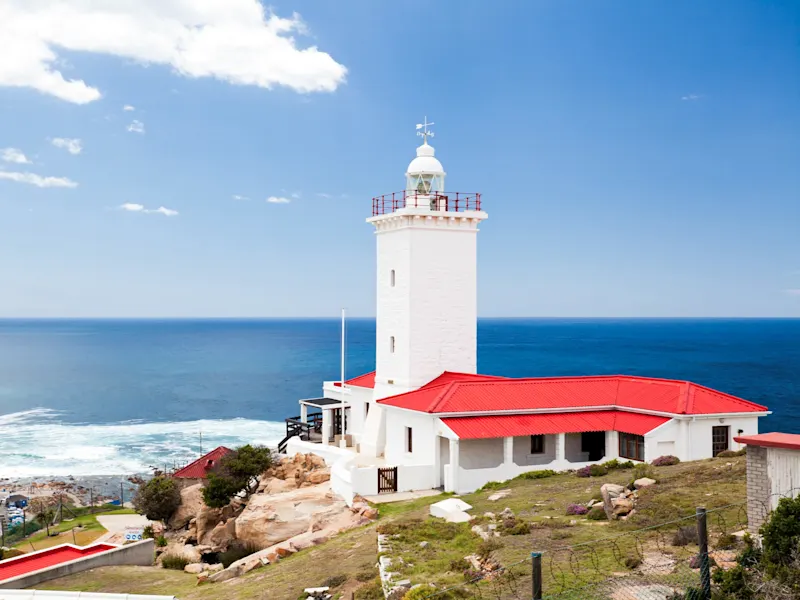 Mossel Bay, Westkap, Südafrika Weißer Leuchtturm mit rotem Dach auf einer Klippe über dem Ozean. Mossel Bay, Westkap, Südafrika.