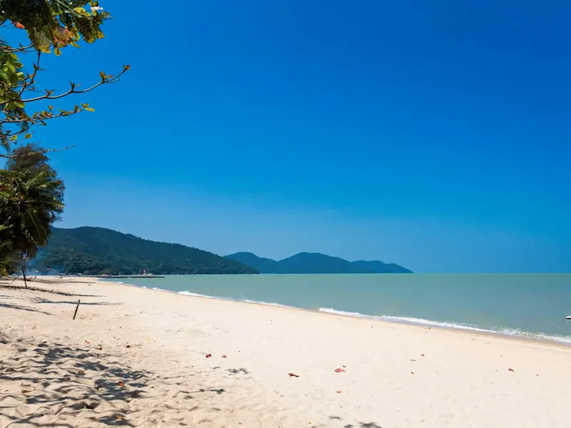 Malaisie, voyage de noces Plage avec ciel bleu, eau calme, palmiers et collines verdoyantes en arrière-plan. Malaisie.