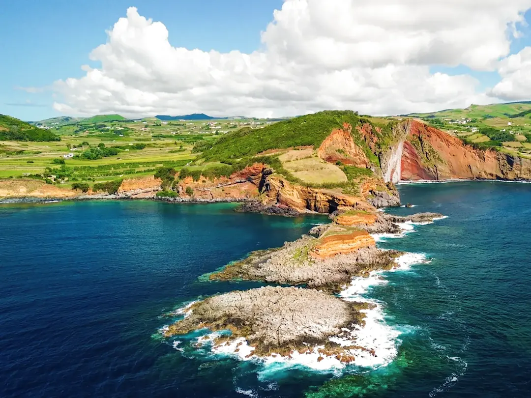 Portugal, Azoren, Terceira Küstenlandschaft mit roten Klippen, türkisblauem Meer und Wasserfall. Terceira, Azoren, Portugal.