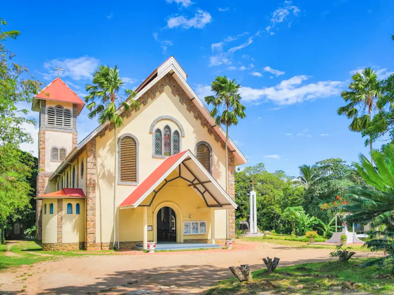 Seychellen, Mahe, Kirche Historische Kirche mit roten Dachziegeln, umgeben von tropischer Vegetation. Mahe, Seychellen.