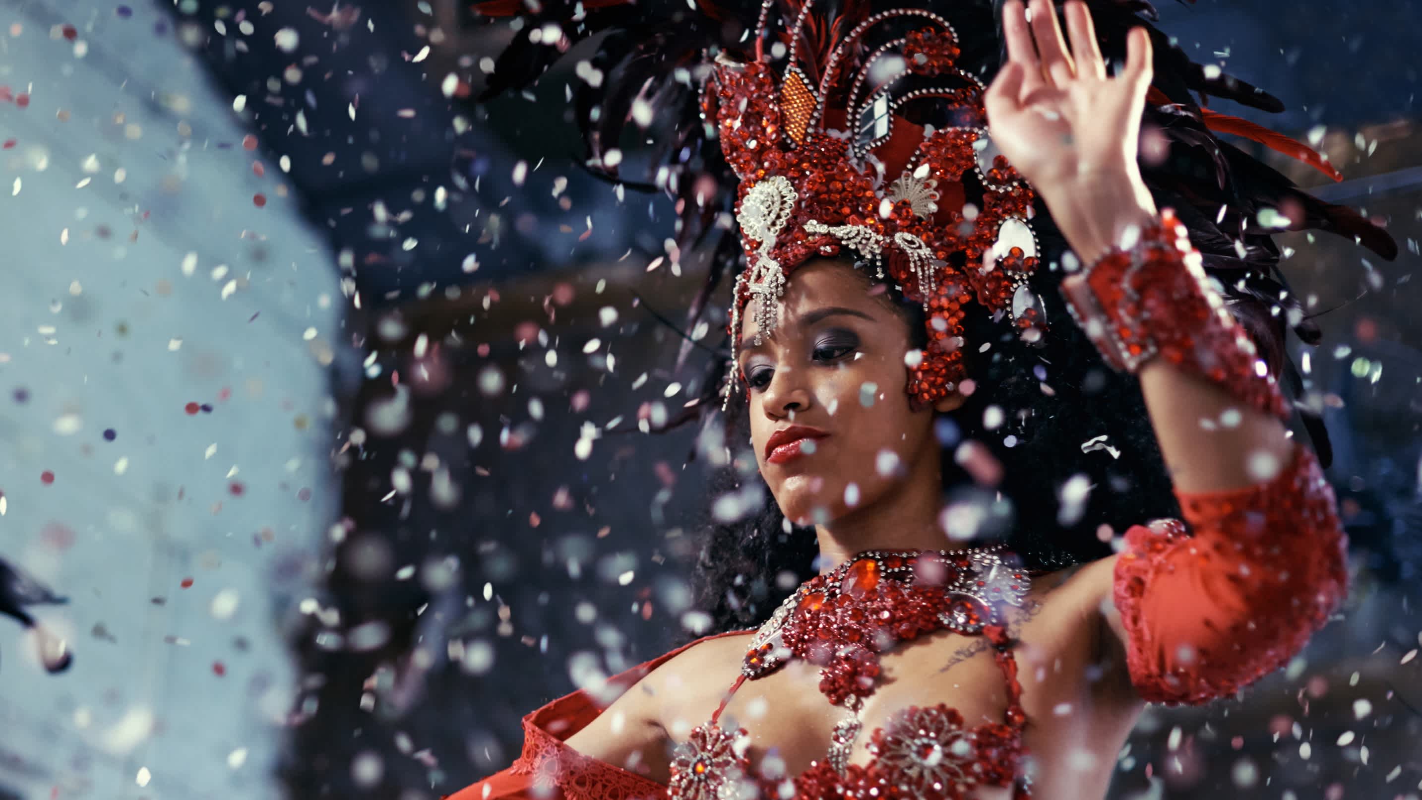 South America, Brazil, Rio de Janeiro, a carnival dancer wearing a feather headdress is showered in confetti