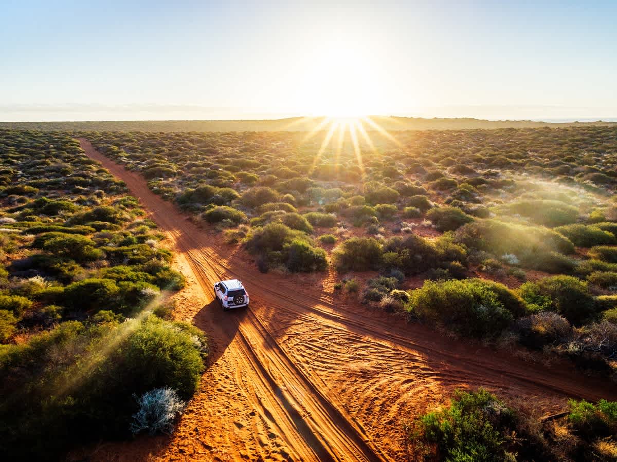 Vue du ciel sur un 4x4 qui traverse le bush australien par une belle journée ensoleillée lors d'une étape d'un circuit de 3 semaines en Australie.