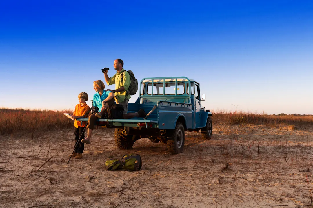 Vater, Mutter und Sohn mit Jeep in der Wildnis beim Familienurlaub in Kenia