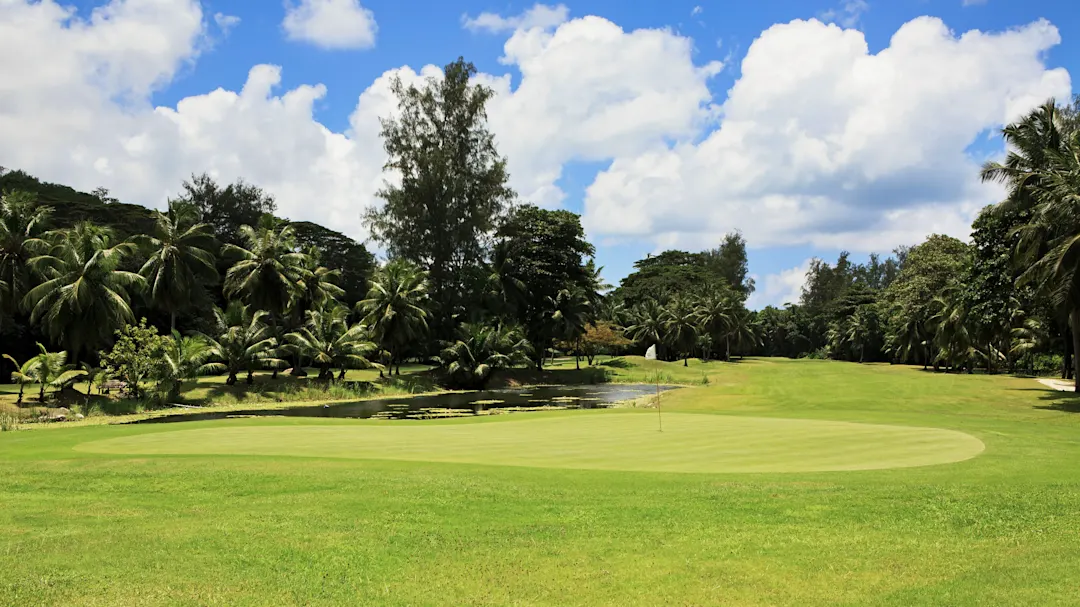 Golfplatz mit Palmen und tropischer Vegetation unter blauem Himmel. Mahé, Seychellen.