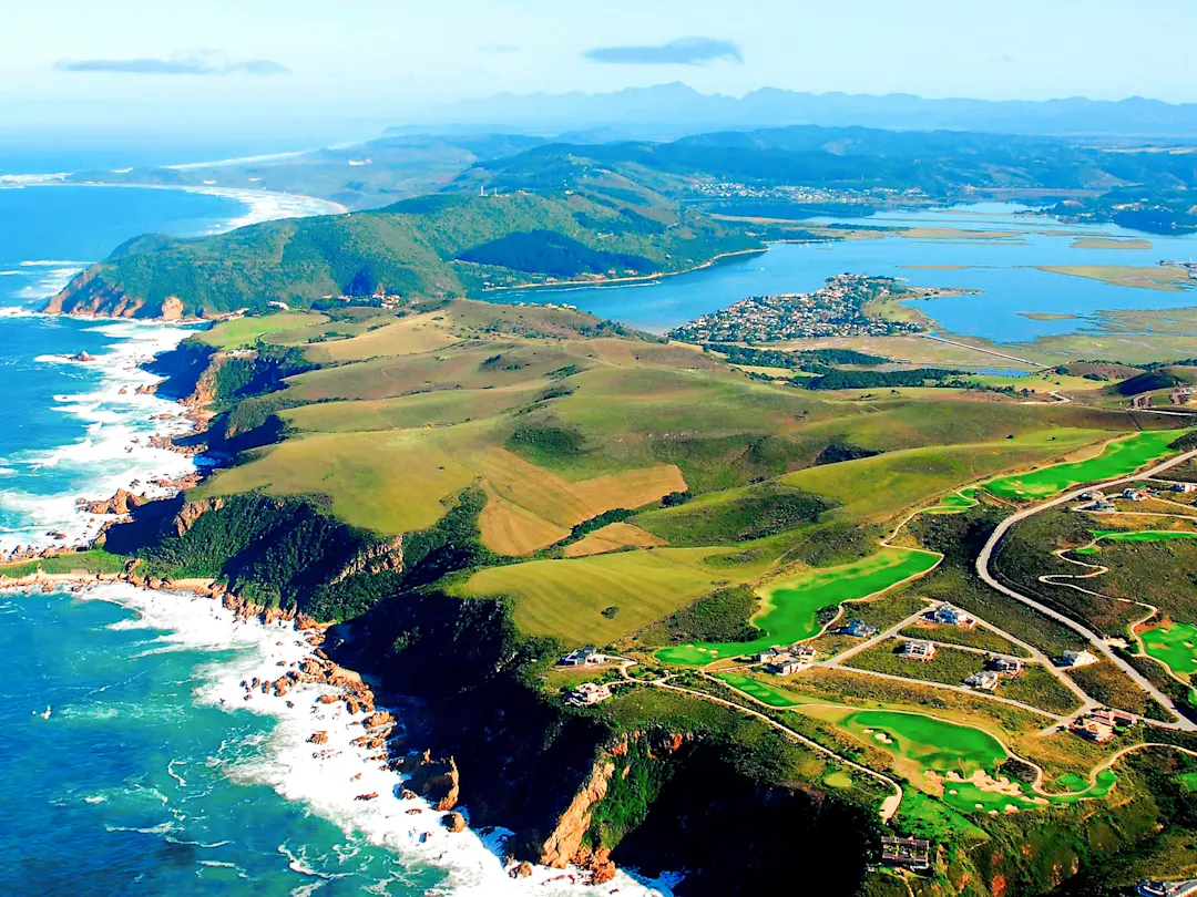 Luftaufnahme einer grünen Küstenlandschaft mit Golfplatz und Ozeanblick. Südafrika.