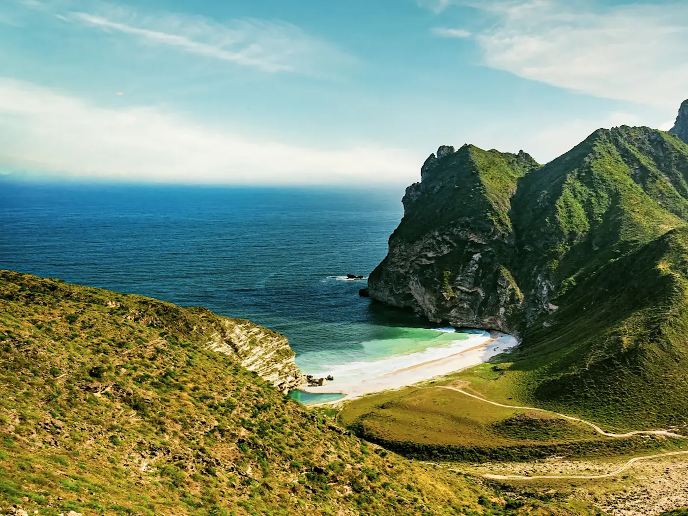 Grüne Klippen mit verstecktem Strand am Meer. Salalah, Dhofar, Oman.
