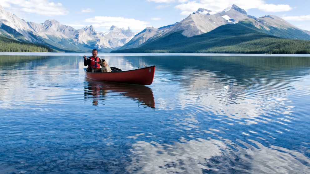 Voyageur dans son kayak accompagné de son chien sur un lac pendant son voyage au Canada.