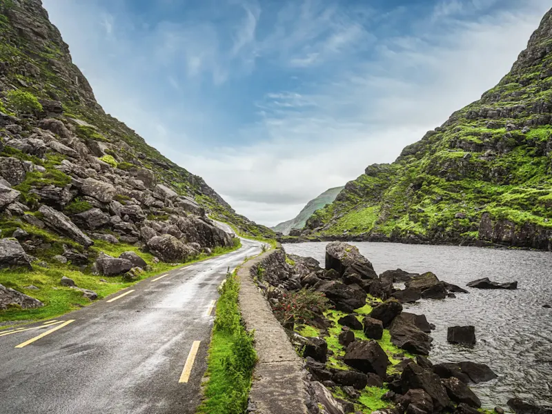 Irlande, Gap of Dunloe, Kerry, road trip Route sinueuse à travers paysage montagneux avec eau et rochers sur le rivage. Kerry, Irlande.