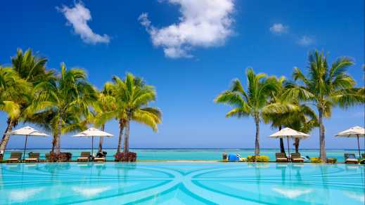 Chaises longues et parasols au bord d'une piscine avec la mer en arrière-plan à l'île Maurice
