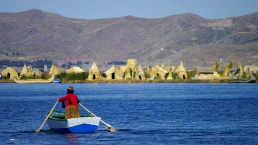 Un habitant pagaie dans un petit bateau sur les îles Uros, lac Titicaca, Pérou.