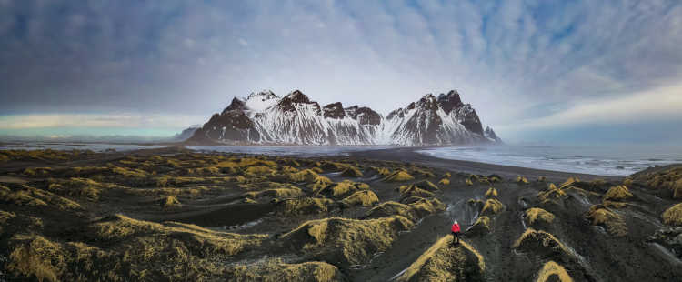 Une randonneuse admirant le panorama de la baie de Stokksnes et la montagne Vestrahorn en Islande.