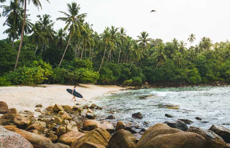 Surferin entspannt am Strand, Tropische Umgebung dahinter