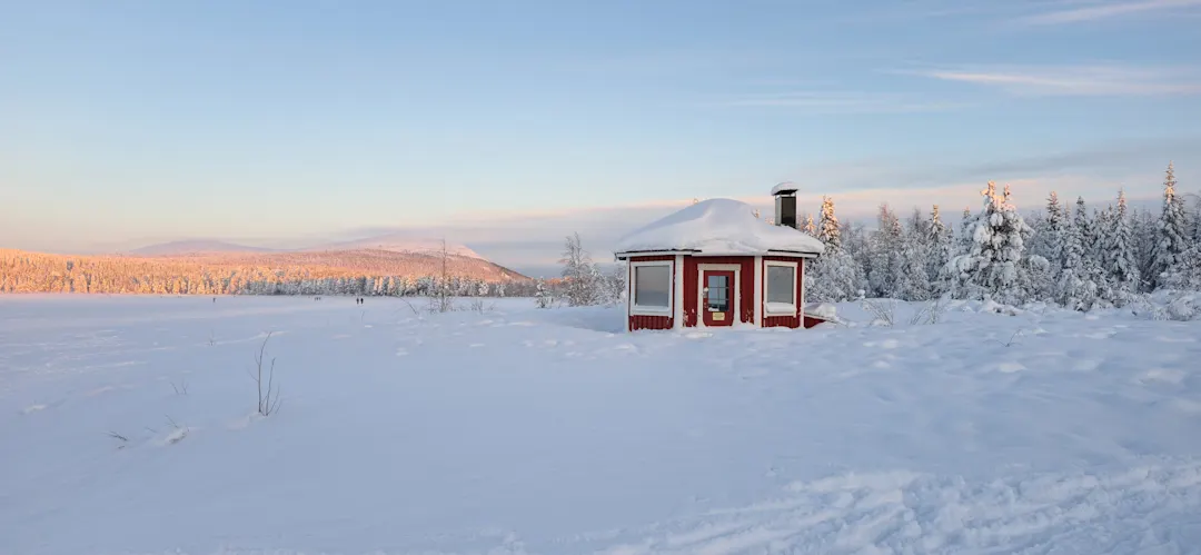 Ein winterliches Wunderland in Akaslompolo, Lappland, mit einer gemütlichen Hütte inmitten einer verschneiten Landschaft
