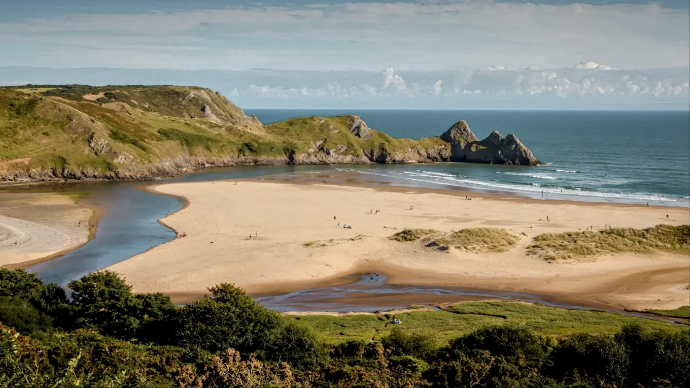 Drei-Klippen-Bucht mit Sandstrand und grünem Hügelpanorama. Swansea, Wales, Vereinigtes Königreich.
